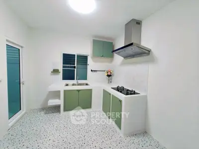 Modern kitchen with green cabinets and gas stove in a bright, minimalist design.