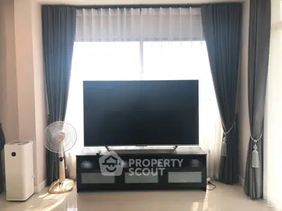 Modern living room with large TV, elegant curtains, and air purifier