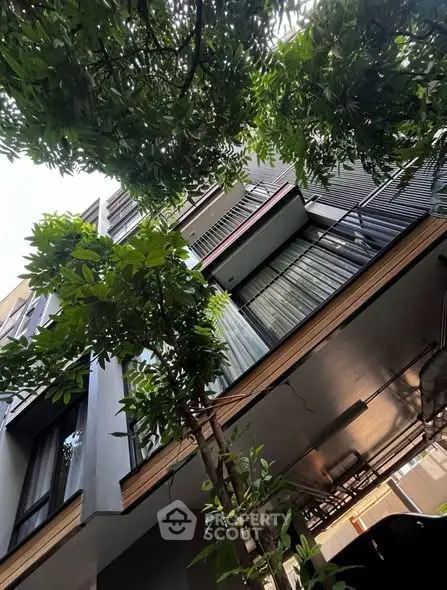 Modern multi-story building exterior with lush greenery and sleek architectural design.