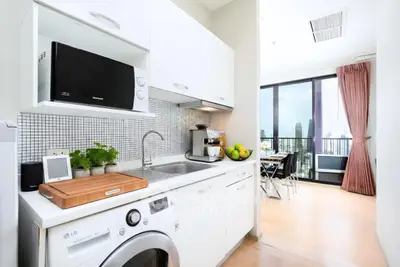 Modern kitchen with sleek appliances and open layout leading to a balcony with city view.