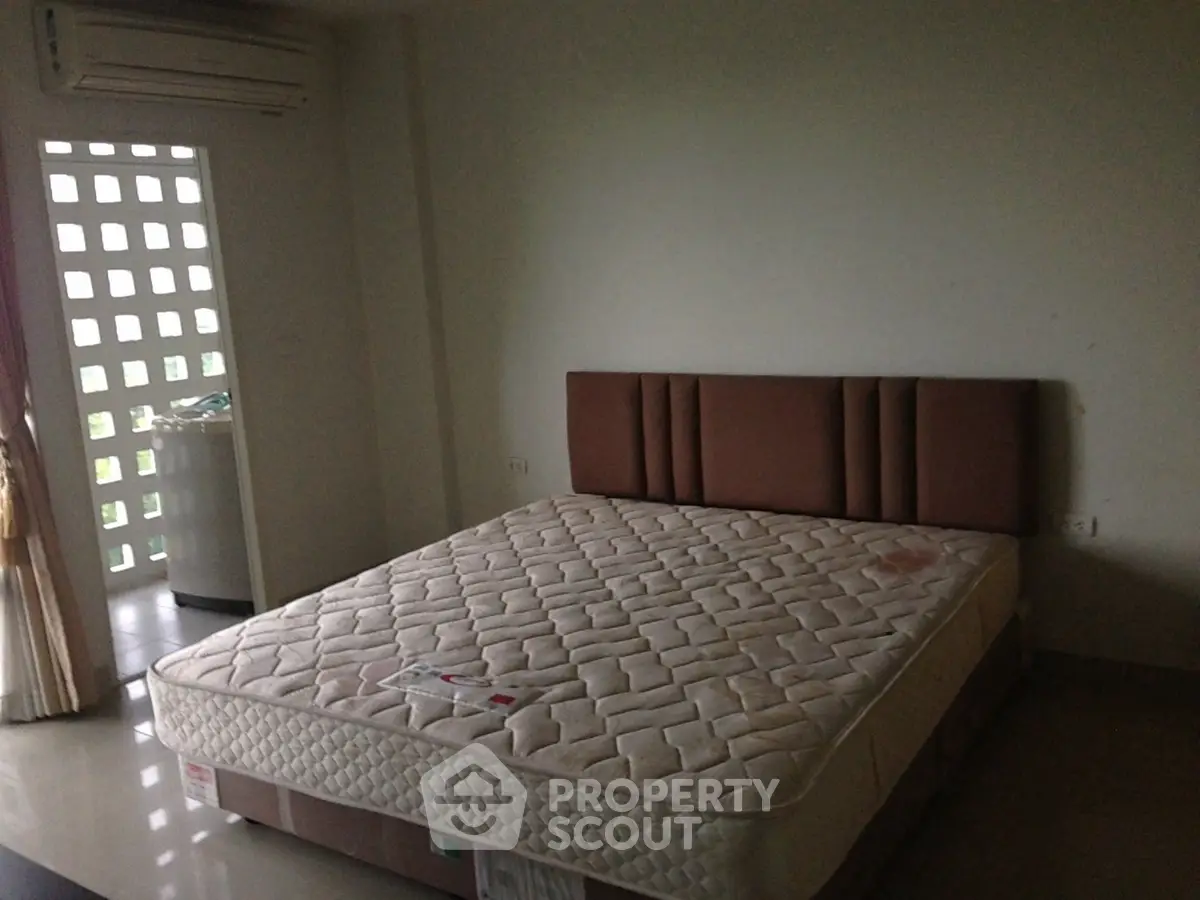 Spacious bedroom with natural light and modern air conditioning unit, perfect for comfort and relaxation.