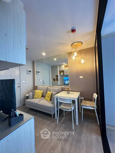 Modern living room with cozy sofa, dining table, and stylish lighting in a compact apartment.
