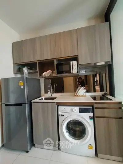 Modern kitchen with sleek cabinets, washing machine, and stainless steel appliances.