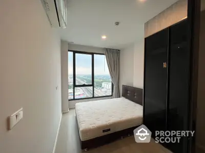 Modern bedroom with large window offering stunning city view and sleek wardrobe design.