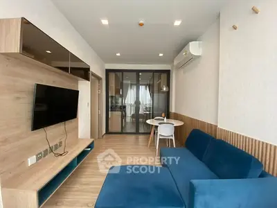 Modern living room with blue sofa and wall-mounted TV in open layout apartment.