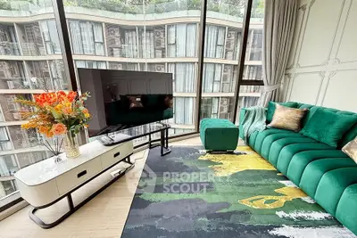 Luxurious living room with modern green sofa, large TV, and stunning city view through floor-to-ceiling windows.