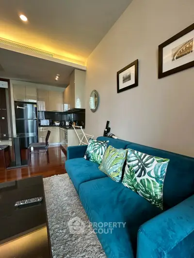 Modern living room with vibrant blue sofa and open kitchen layout.