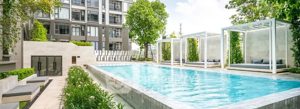 Luxurious condominium pool area with modern cabanas and lush greenery