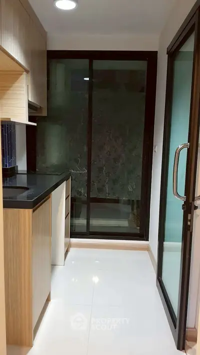 Modern kitchen with sleek cabinetry and large glass sliding door for natural light.