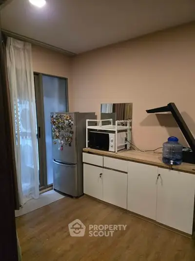 Cozy kitchen with fridge, microwave, and ample storage in modern apartment.