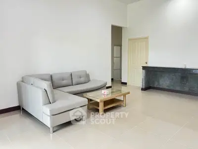 Spacious modern living room with sleek gray sofa and glass coffee table.