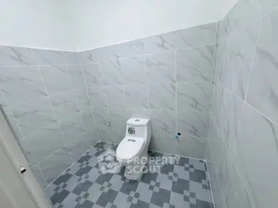 Modern bathroom with sleek tiled walls and floor featuring a compact toilet.