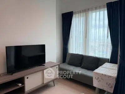 Modern living room with TV, sofa, and large windows offering city views.