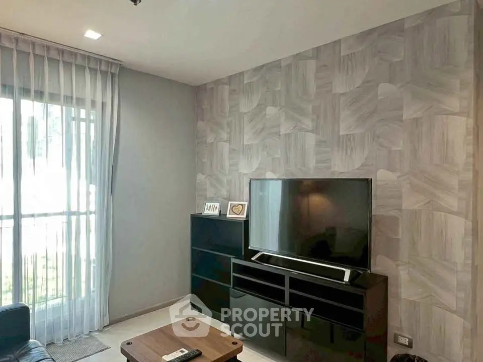 Modern living room with stylish wallpaper and large TV, perfect for entertainment and relaxation.