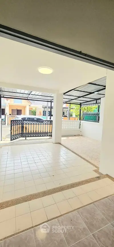 Spacious covered patio with tiled flooring and modern railing, perfect for outdoor relaxation.
