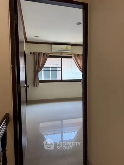 Spacious empty room with large window and air conditioning, perfect for customization.