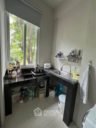 Compact kitchen with large window and modern appliances, offering a bright and efficient cooking space.