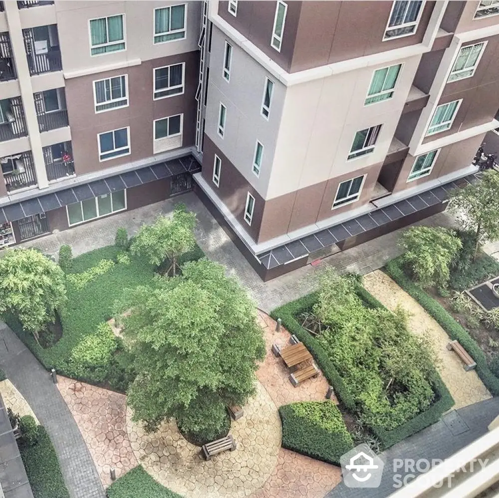 Stunning aerial view of modern apartment complex with lush landscaped garden and seating area.