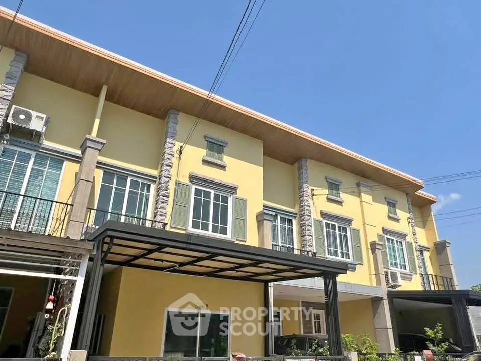 Charming yellow townhouse with modern facade and ample natural light.