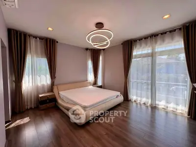 Spacious bedroom with modern lighting and large windows for natural light.