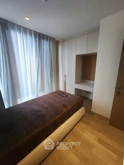 Modern bedroom with sleek design and natural light, featuring a cozy bed and built-in storage.