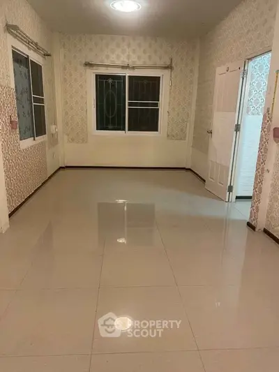 Spacious empty room with glossy tiled floor and patterned wallpaper, ideal for customization.