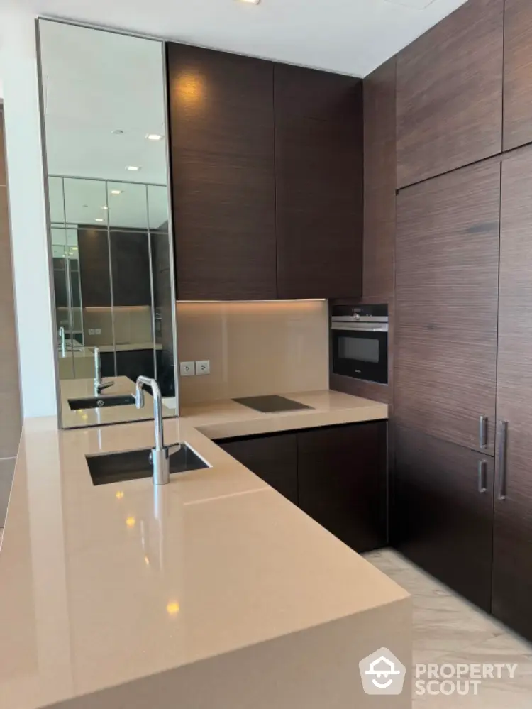 Modern kitchen with sleek dark wood cabinets and integrated appliances