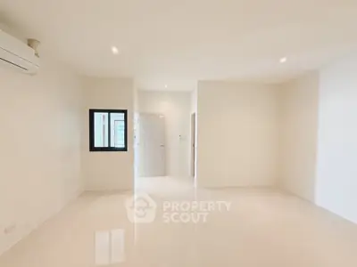 Spacious minimalist living room with sleek white flooring and modern lighting.
