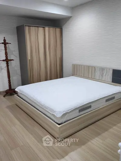 Modern bedroom with stylish wooden wardrobe and minimalist bed frame.