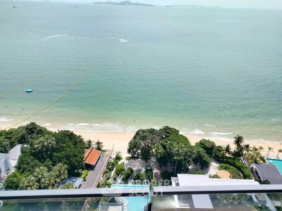 Stunning beachfront view from high-rise balcony overlooking serene ocean and lush greenery.