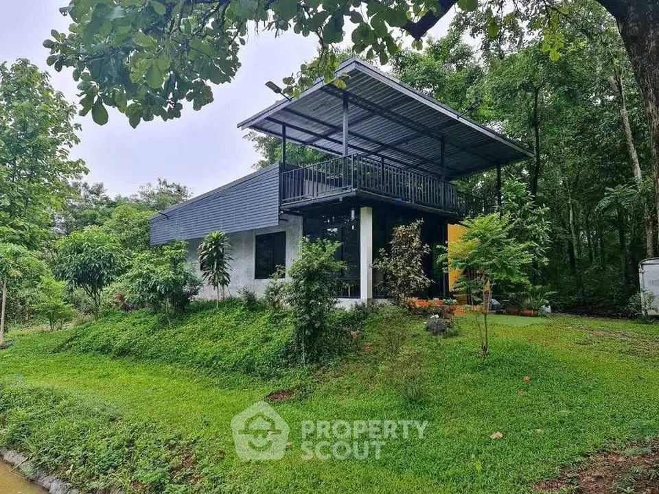Modern two-story house with lush green surroundings and spacious balcony.