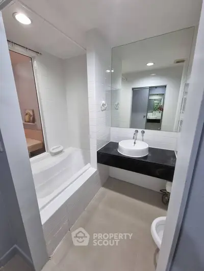 Modern bathroom with sleek design featuring a bathtub and stylish sink area.