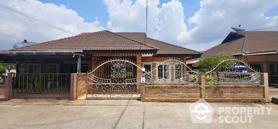 Charming single-story home with ornate metal gate and brick facade under a clear blue sky.