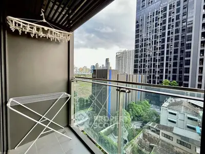 Modern balcony with city view in high-rise building, featuring drying rack and glass railing.