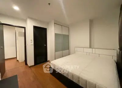 Modern bedroom with wooden flooring and built-in wardrobe in a cozy apartment.