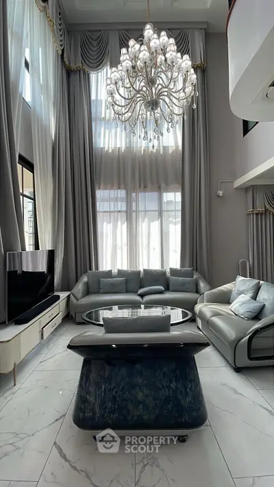 Luxurious living room with high ceilings, elegant chandelier, and modern furniture.