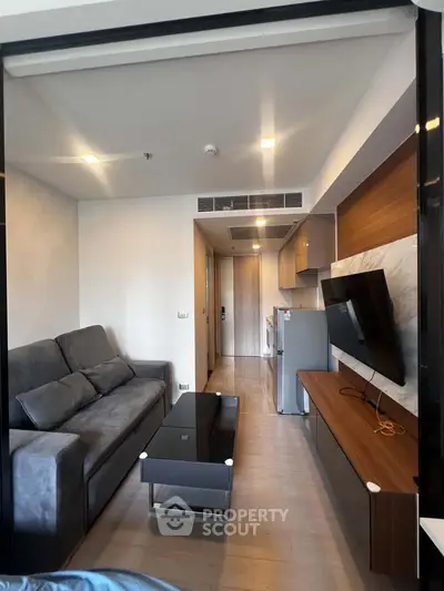 Modern living room with sleek furniture and wall-mounted TV in a stylish apartment.