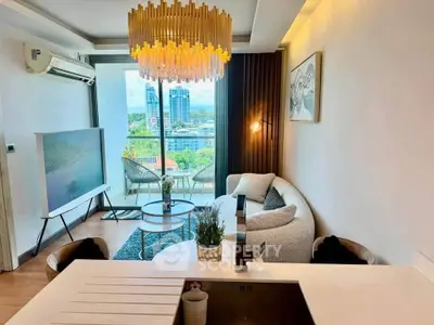Modern living room with elegant chandelier and city view, featuring cozy seating and stylish decor.