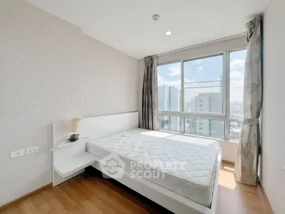 Bright bedroom with large windows offering city views, featuring a modern bed and wooden flooring.