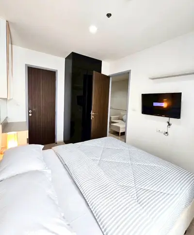 Modern bedroom with sleek design, featuring a wall-mounted TV and stylish bedding.