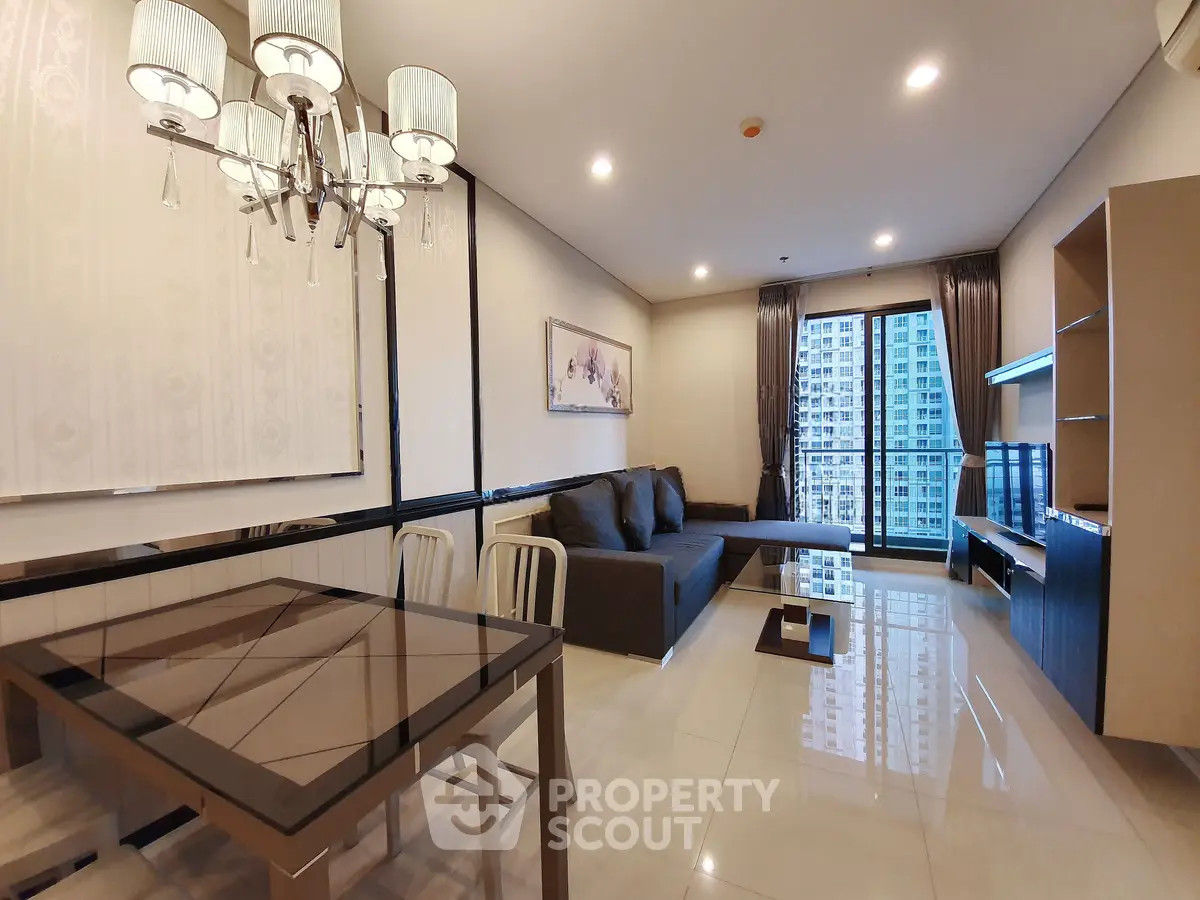 Spacious modern living room with elegant chandelier and city view balcony.