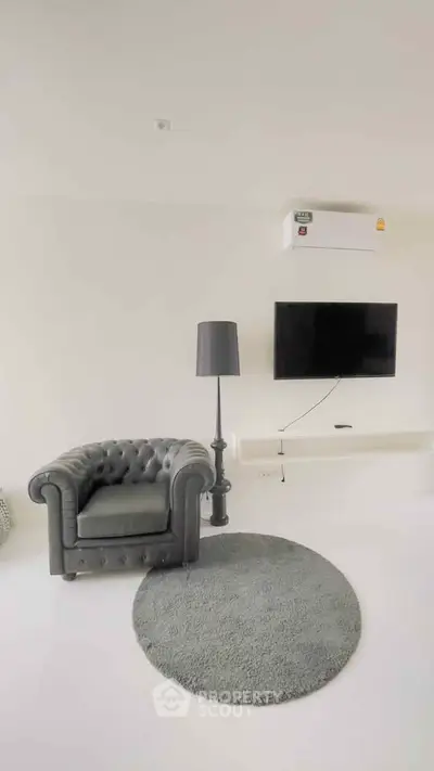 Modern living room with stylish armchair, wall-mounted TV, and sleek decor.