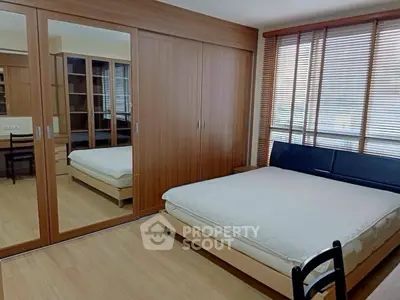 Spacious bedroom with mirrored wardrobe and large windows for natural light.