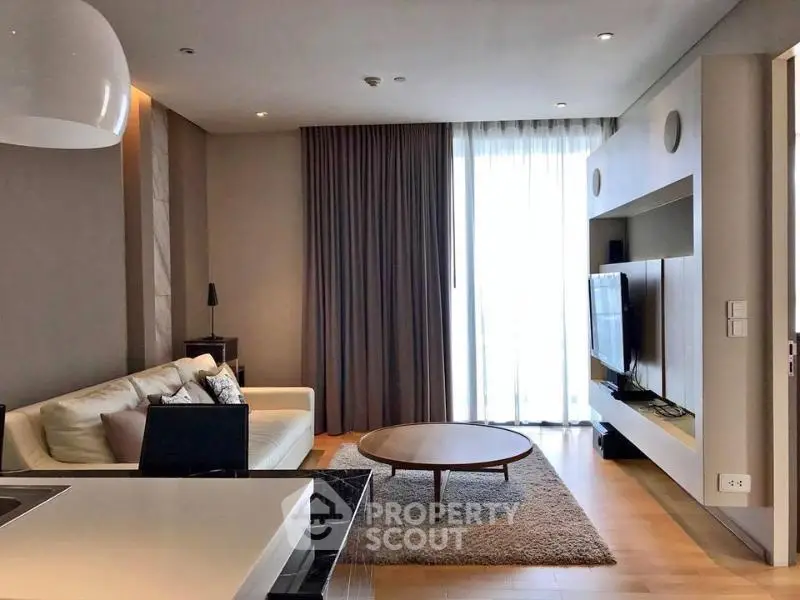 Modern living room with stylish decor and natural light, featuring a cozy sofa and sleek entertainment unit.