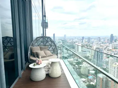 Luxurious high-rise balcony with stunning cityscape view and cozy seating area.