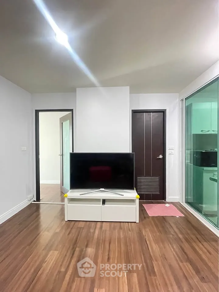 Modern living room with sleek TV stand and glass partition to kitchen