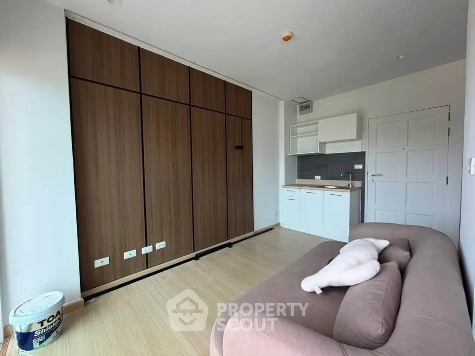 Modern living room with sleek wooden cabinets and compact kitchen area