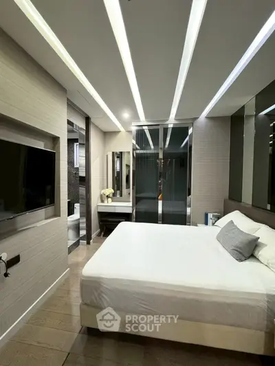Modern bedroom with sleek design, featuring a large bed, built-in TV, and stylish lighting.