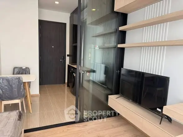 Modern apartment interior with open layout, featuring sleek furniture and a compact kitchen area.