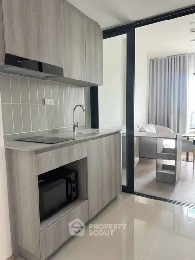 Modern kitchen with sleek cabinetry and open layout adjacent to a cozy living area.